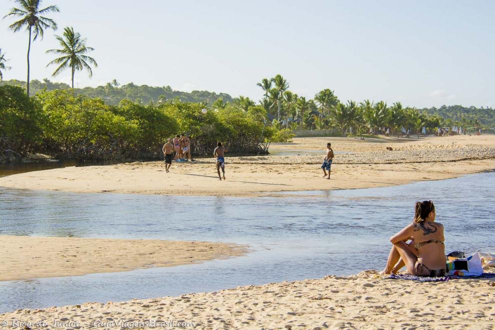 Imagem de uma moça sentada próxima a piscina natural da Praia dos Nativos.